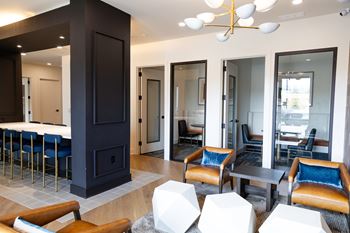 A modern living room with a dark wood fireplace and blue chairs at The Crest at South Point Apartments, Davenport , GA, 30253